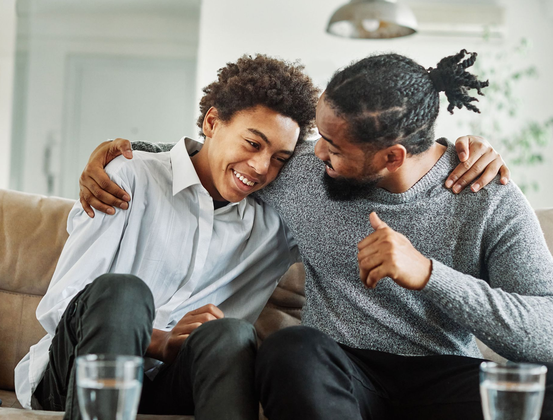 Girl with glasses hugs smiling woman.