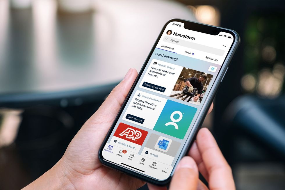 A person holding a smartphone displaying a user interface with various app icons.