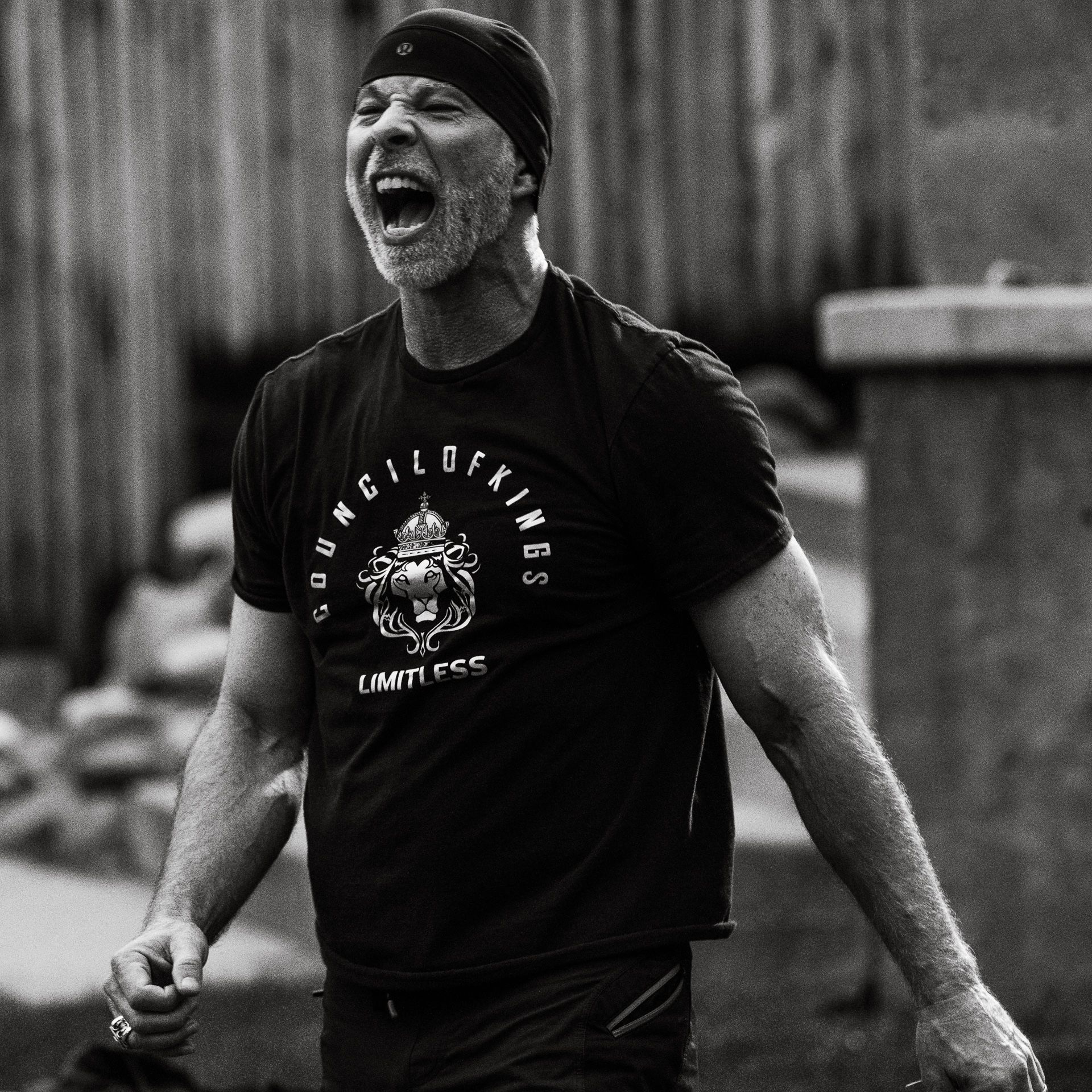 Black-and-white photo of a man roaring like a lion in a workout shirt.