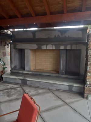Outdoor fireplace under construction; gray concrete with a wooden ceiling and tiled patio.
