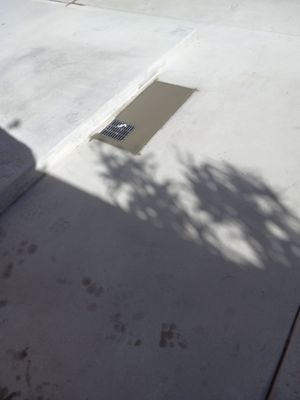 Concrete sidewalk with a rectangular drain partially filled with fresh concrete.