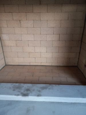Brick fireplace interior; light tan brick walls and floor, gray concrete base.
