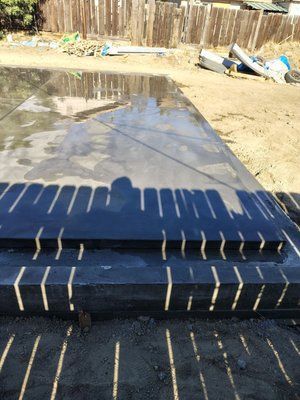 Wet concrete patio and steps casting long shadows on a sunny day.