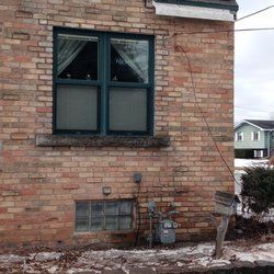 Brick building with green-framed window. A mailbox is visible in front.