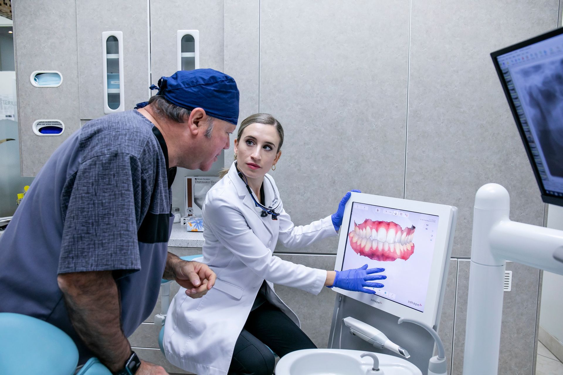 Dentist shows patient dental x-ray on screen in office.