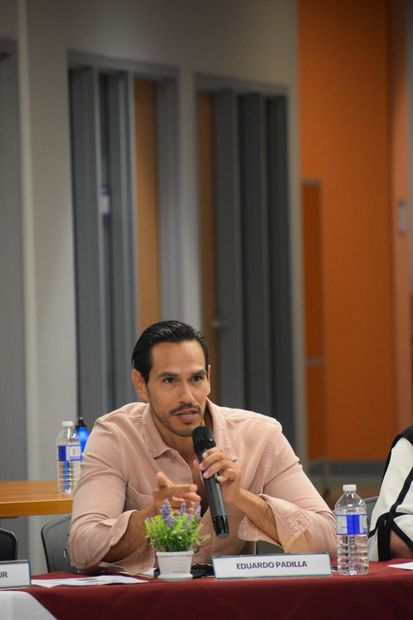 A man is sitting at a table holding a microphone.