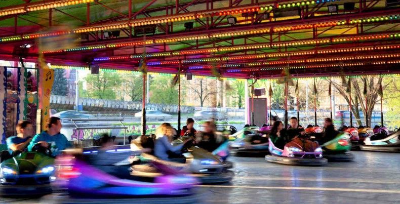 a group of people are riding bumper cars at an amusement park .