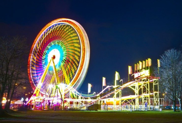 a roller coaster and ferris wheel are lit up at night