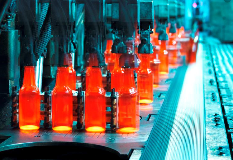 a conveyor belt filled with glass bottles in a factory