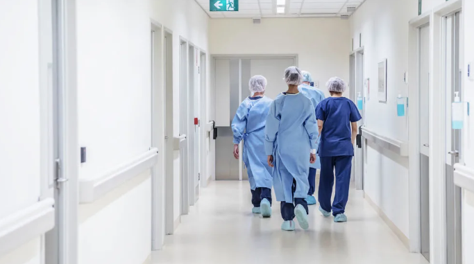a group of doctors and nurses are walking down a hospital hallway .