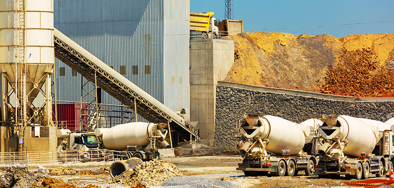 a row of concrete mixers are parked in front of a building at a construction site .