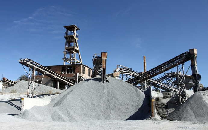 a large pile of gravel is sitting in front of a factory