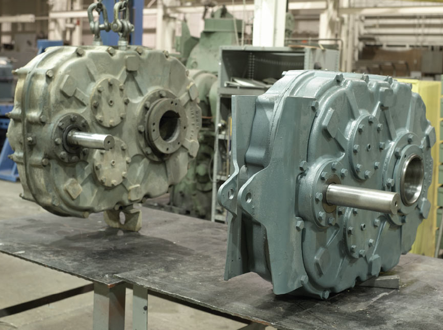 two gearboxes are sitting on a table in a factory .