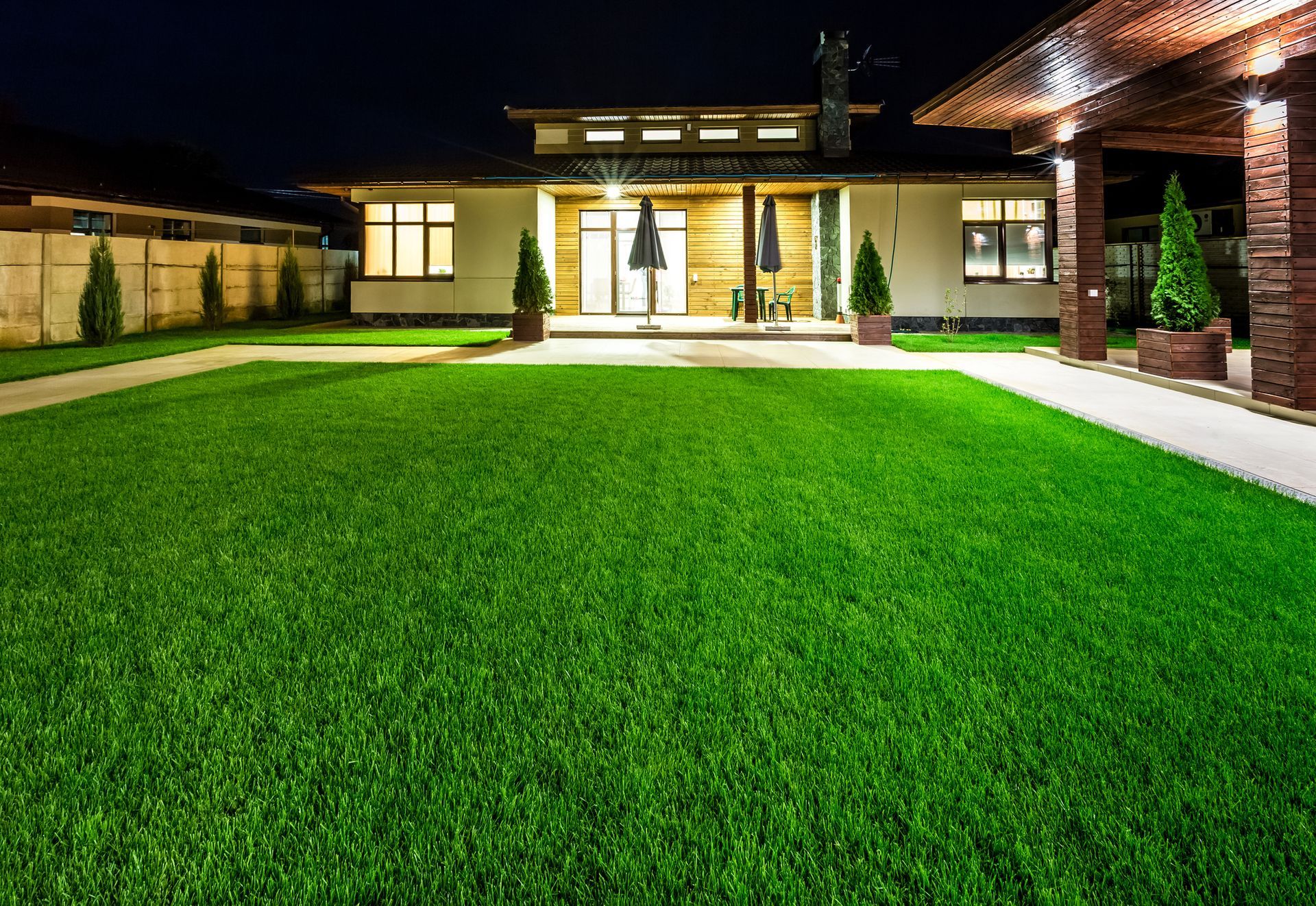A house with a large lawn in front of it at night.