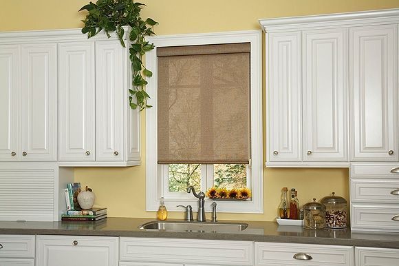 Kitchen with white cabinets, a window with a tan shade, and a sink against a yellow wall.