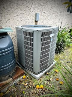 A large air conditioner is sitting on the ground in front of a building.