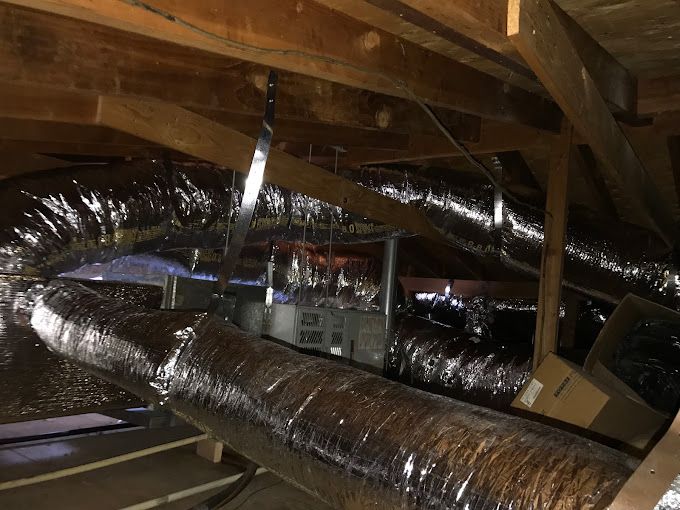 A bunch of ducts are hanging from the ceiling of a building.