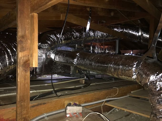 An attic with a lot of pipes and wires