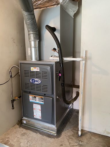 A gas furnace is sitting in a room next to a wall.