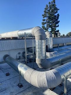 A bunch of pipes are connected to each other on the roof of a building.