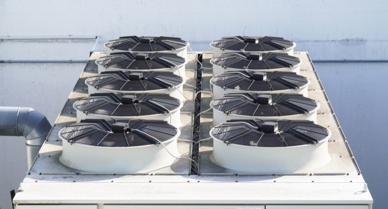 There are a lot of fans on the roof of a building.