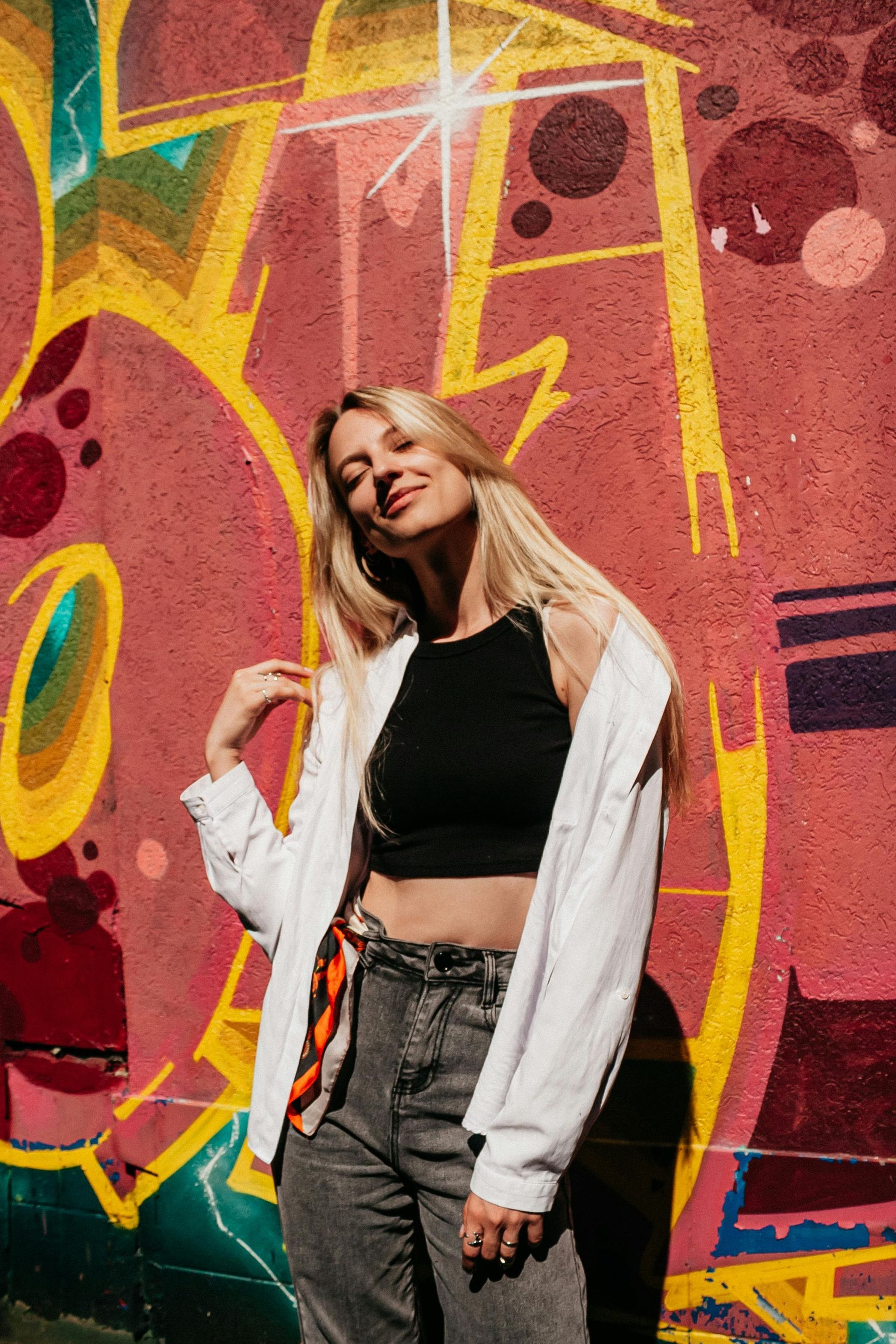 A woman is standing in front of a graffiti wall.