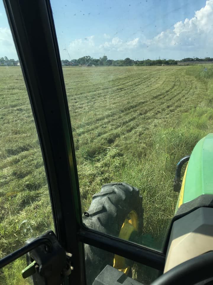 A person is driving a tractor through a grassy field.
