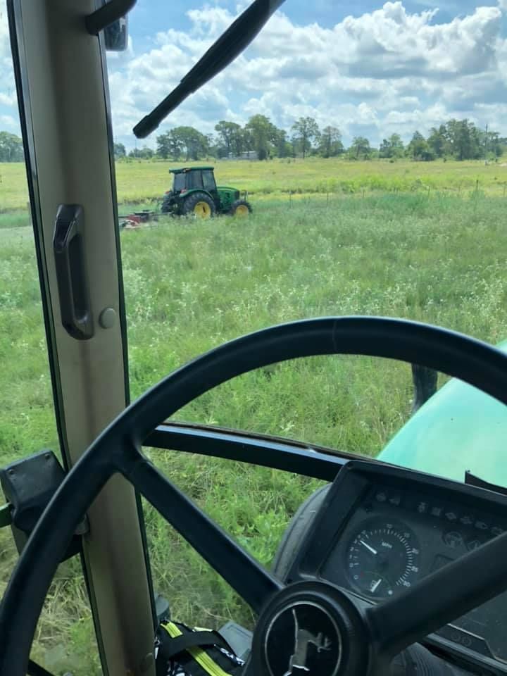 A john deere tractor is driving through a grassy field.