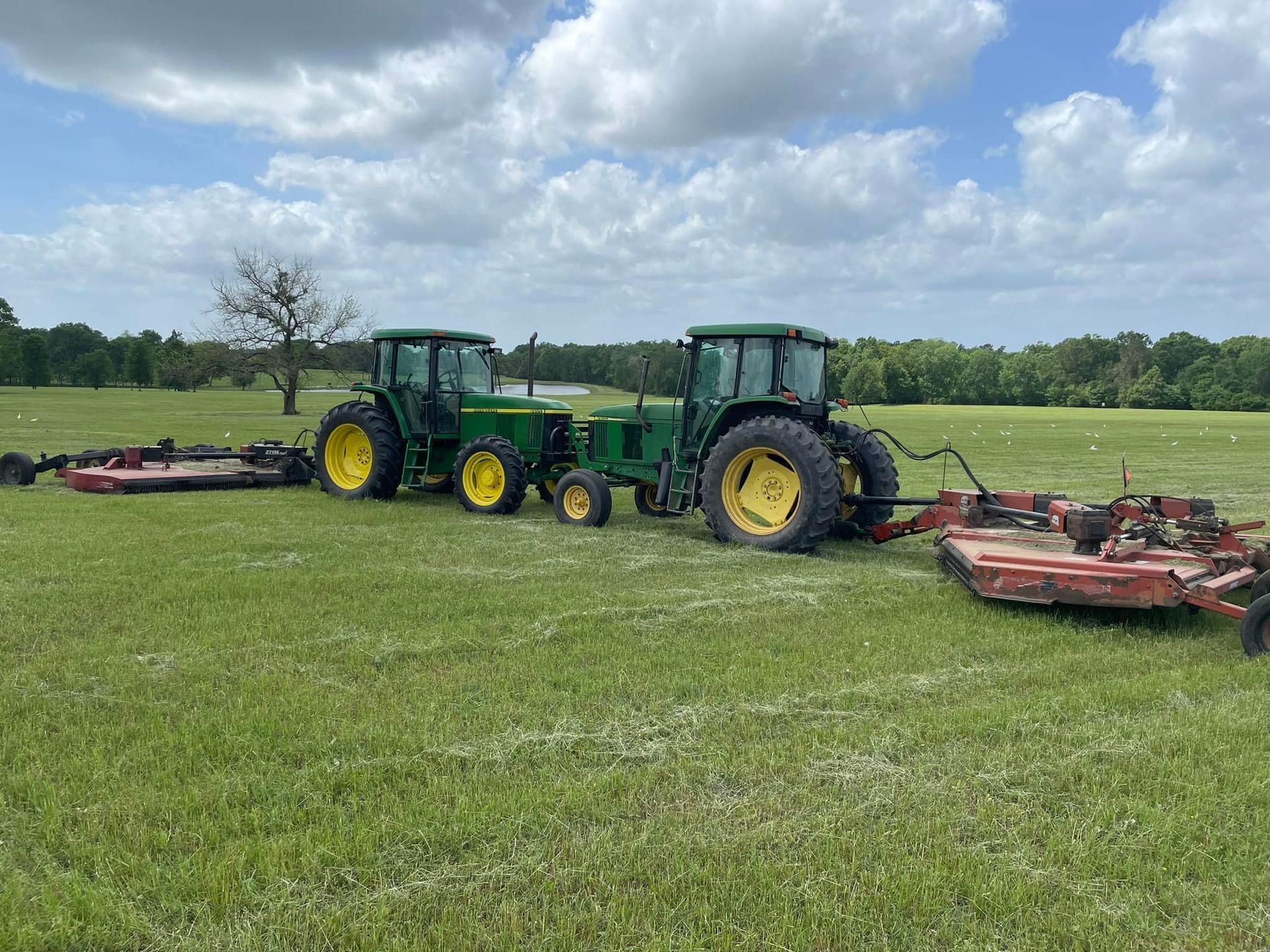 Two john deere tractors are parked in a grassy field.