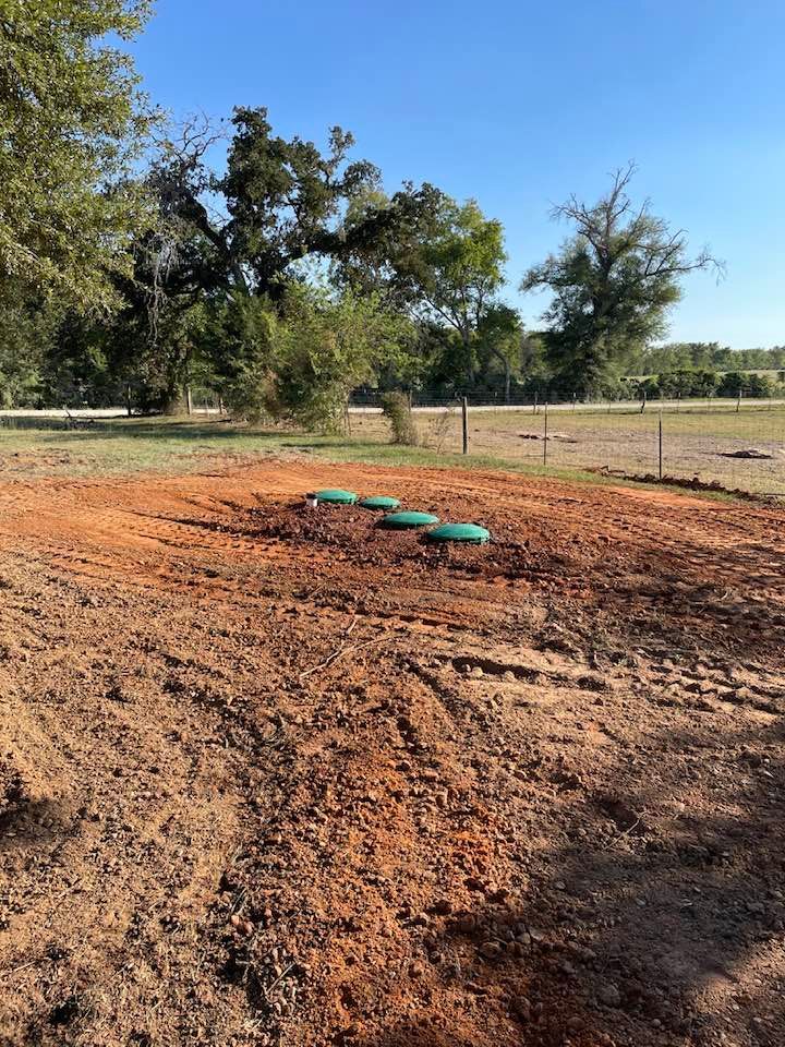There is a septic tank in the middle of a dirt field.