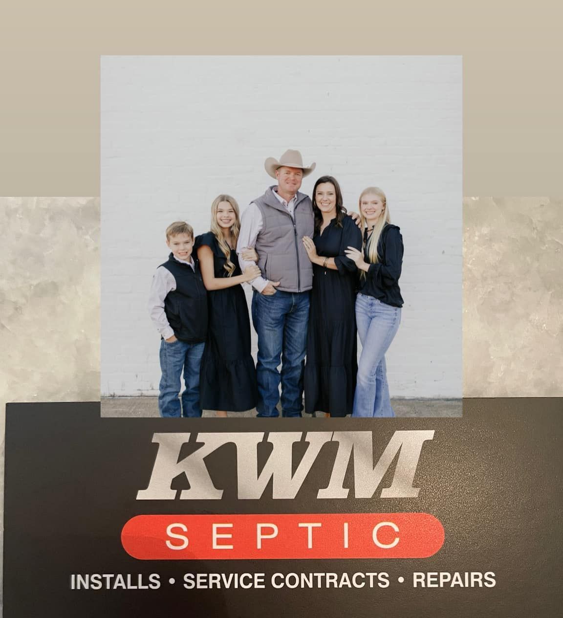 Family posing in front of a white wall above a business card for KWM Septic.