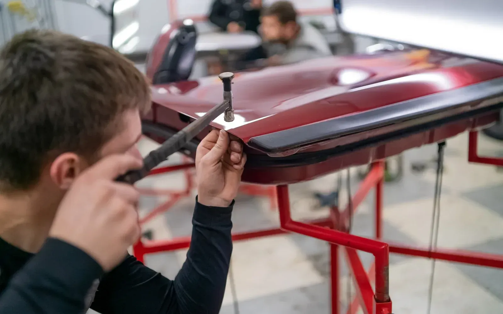 A man is working on a red car in a garage.