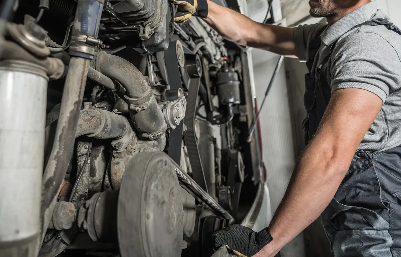 A man is working on a truck engine in a garage.