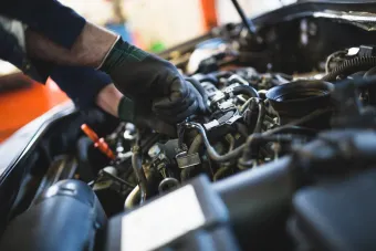 A man is working on the engine of a car in a garage.