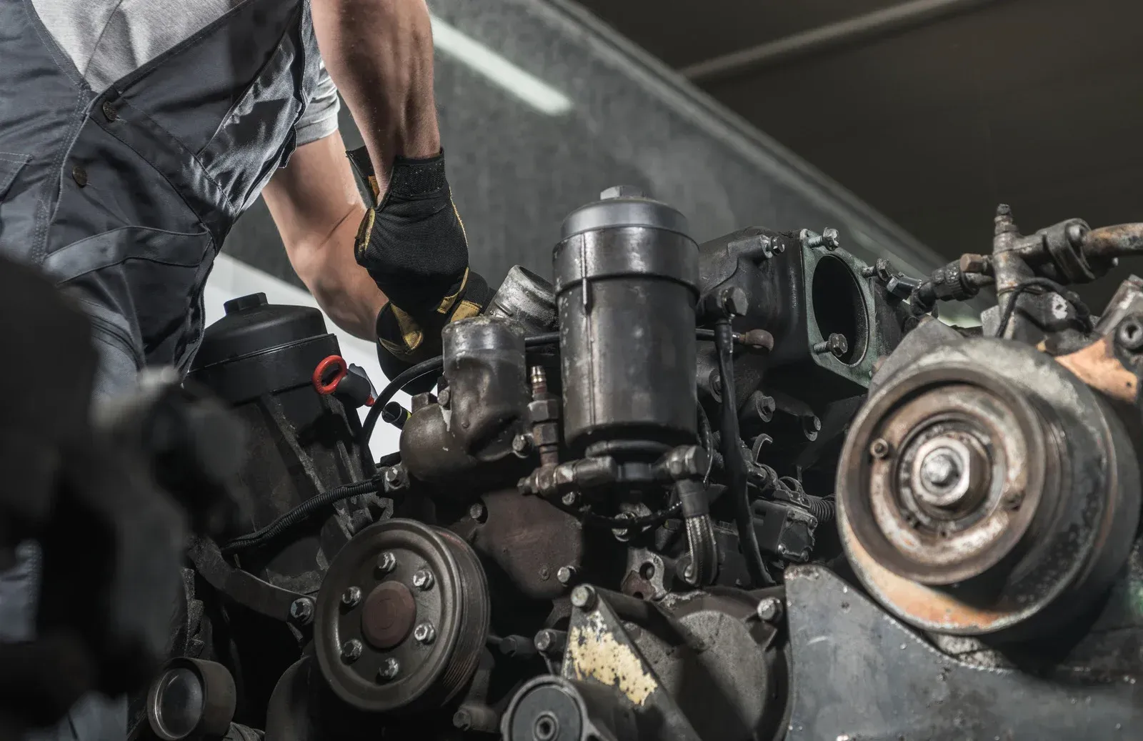 A man is working on a diesel engine in a garage.