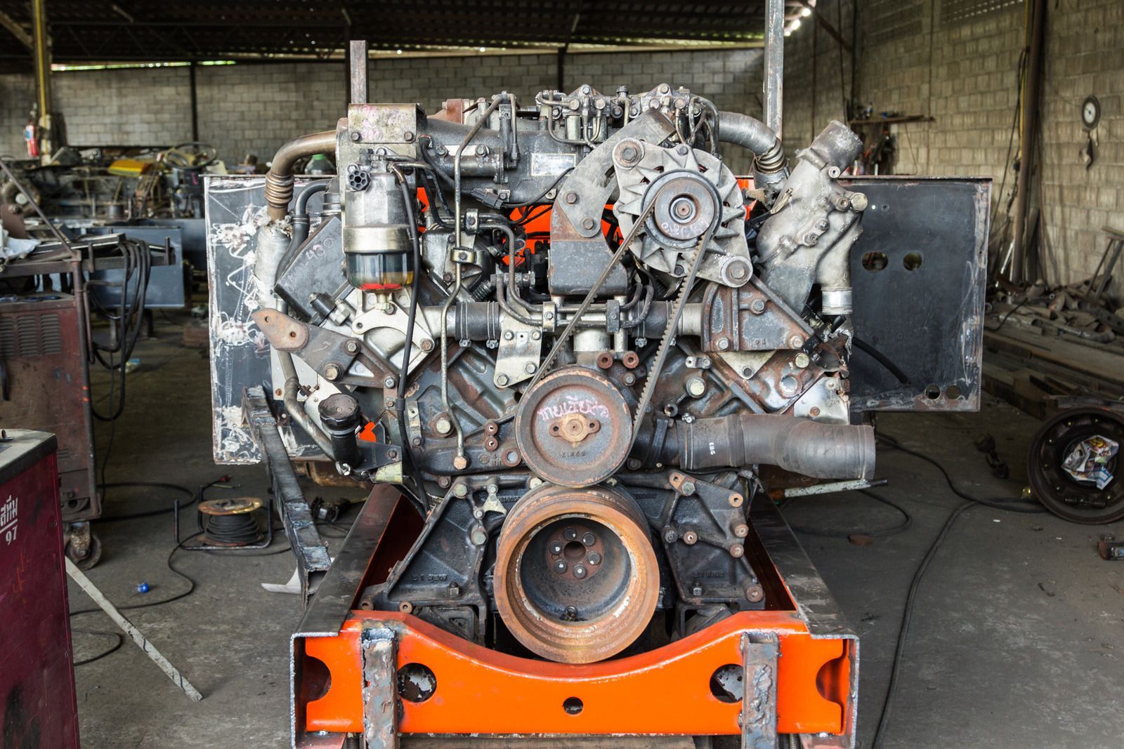 A large engine is sitting on a cart in a garage.