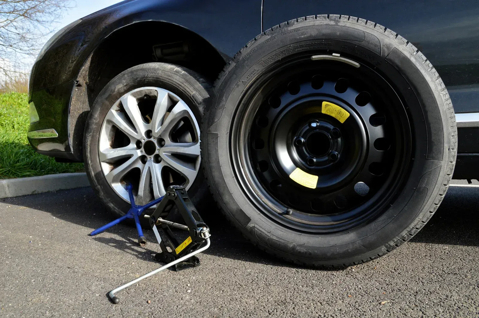 A car with a spare tire and a jack next to it.