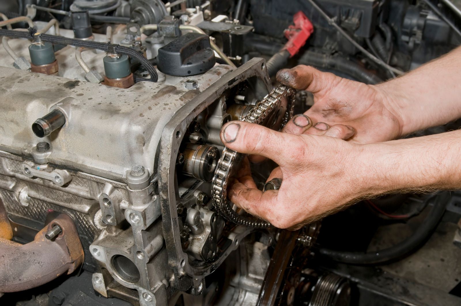 A person is working on a car engine with their hands.