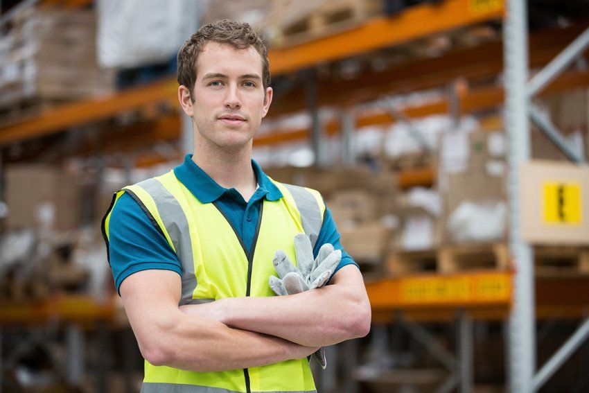 Man with arms folded in warehouse, portrait