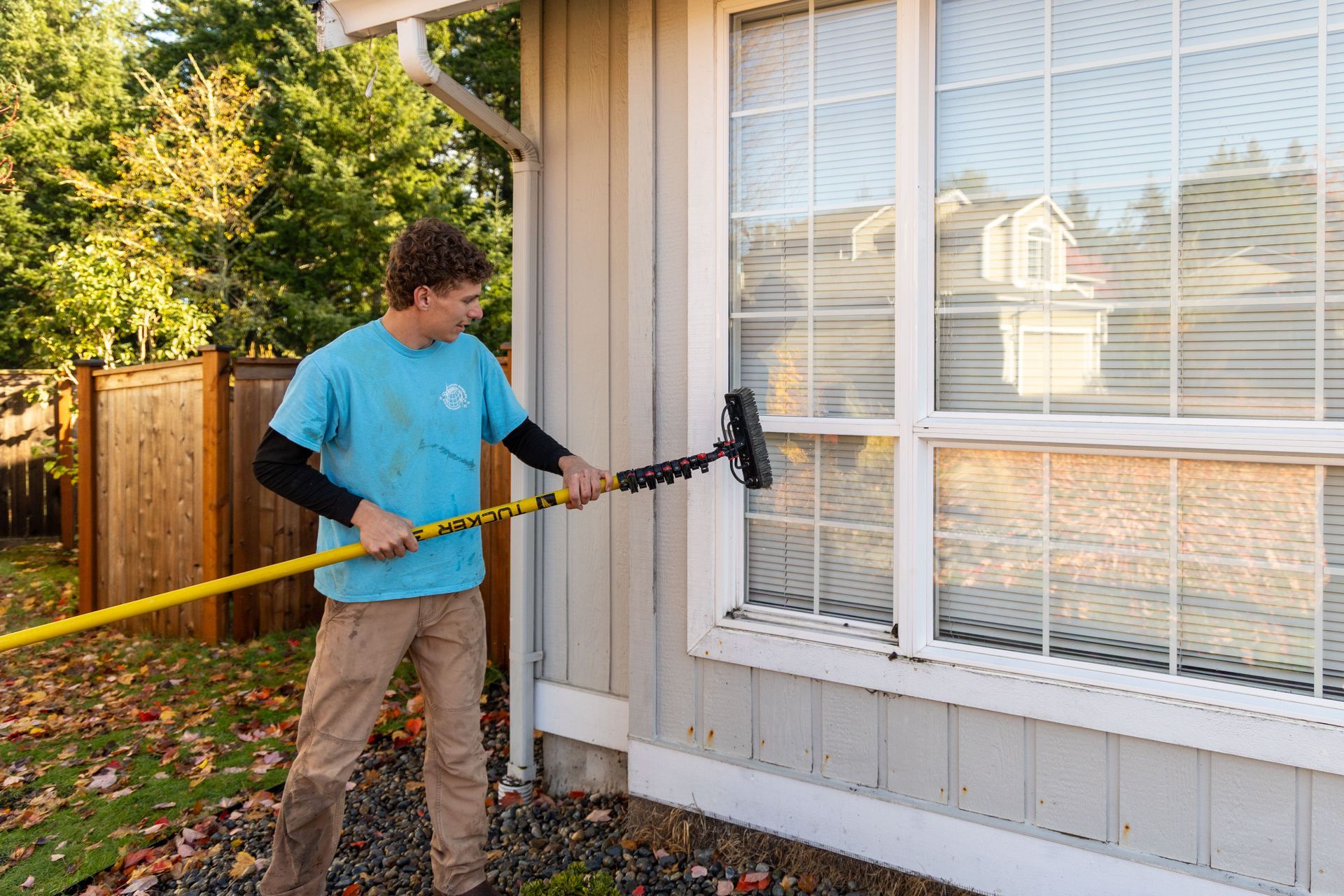 Person using a squeegee to clean a glass window, removing water with a steady motion.