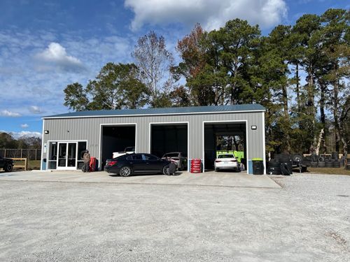 A Car Is Parked In A Gravel Lot In Front Of A Garage - Leland, NC - Skip's Tire Center