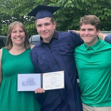 A man in a graduation cap and gown is posing for a picture with his family.