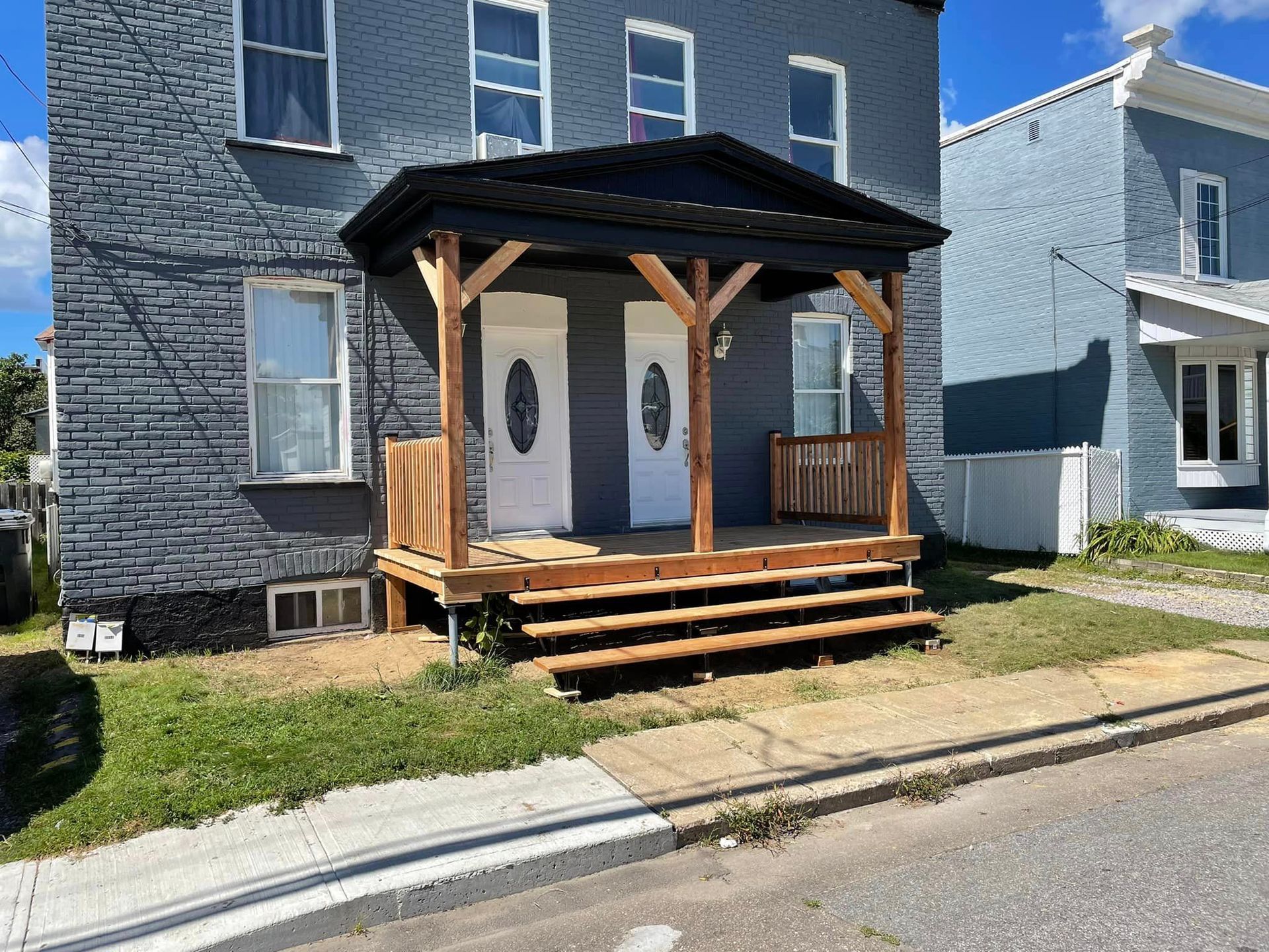 Une maison en brique avec un porche en bois et des escaliers devant.