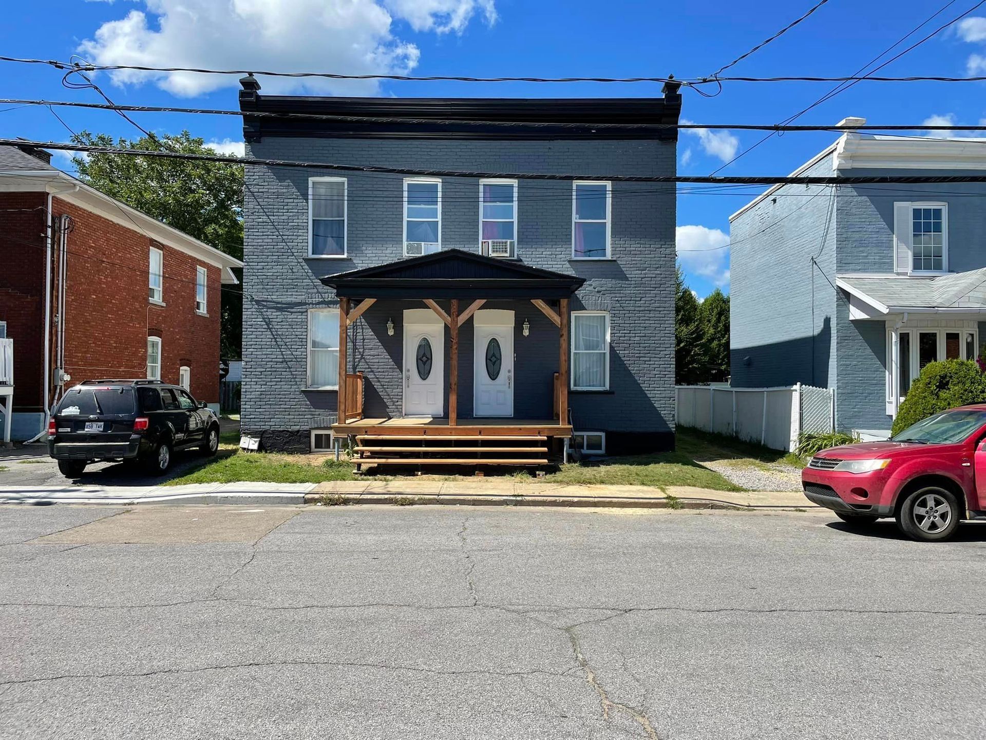 Une voiture rouge est garée devant un bâtiment gris.