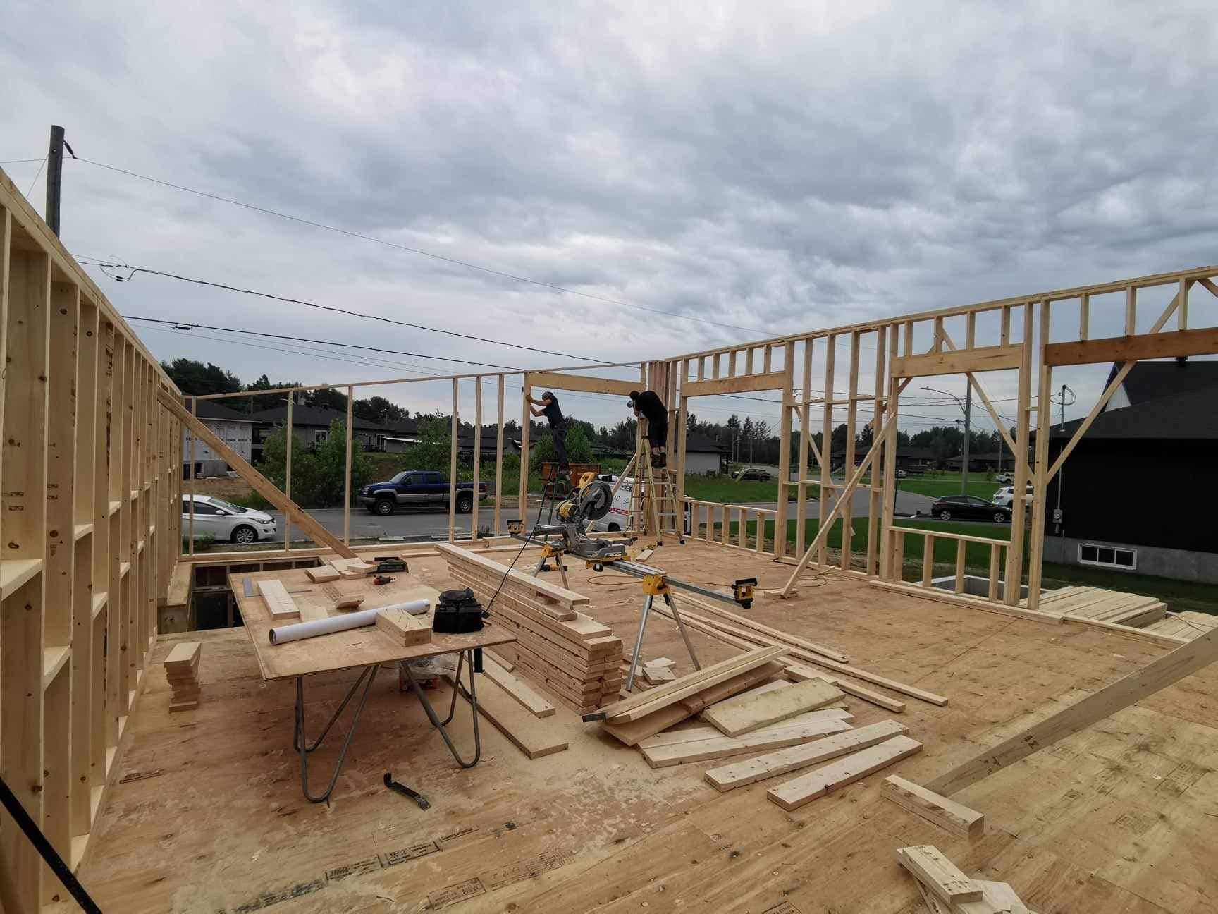 Une maison est en train d'être construite avec beaucoup de bois.