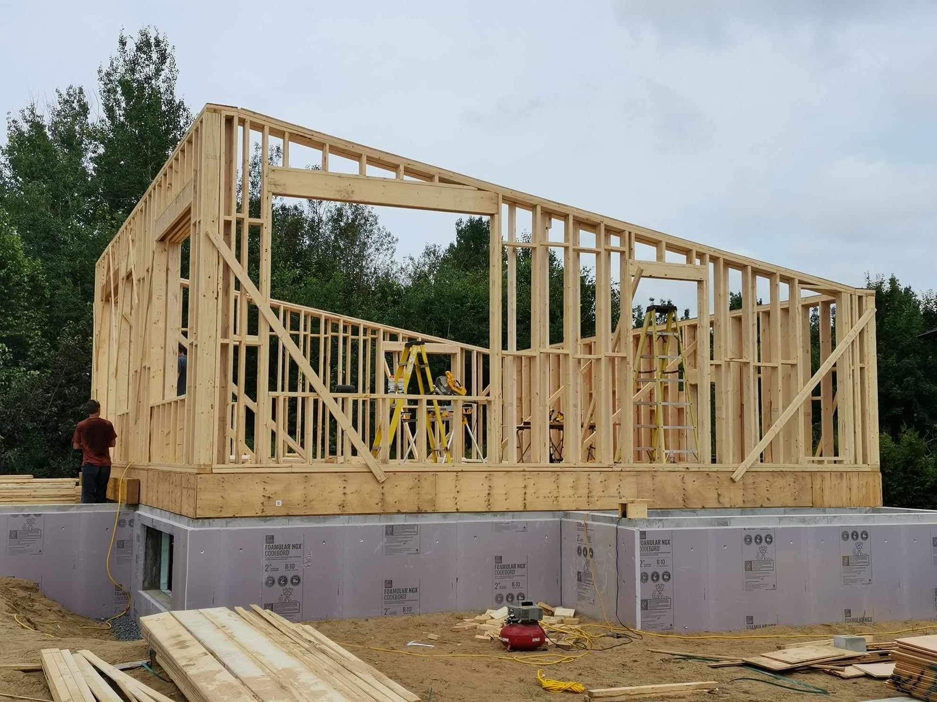 Une maison en bois est en construction au milieu d'un champ de terre.