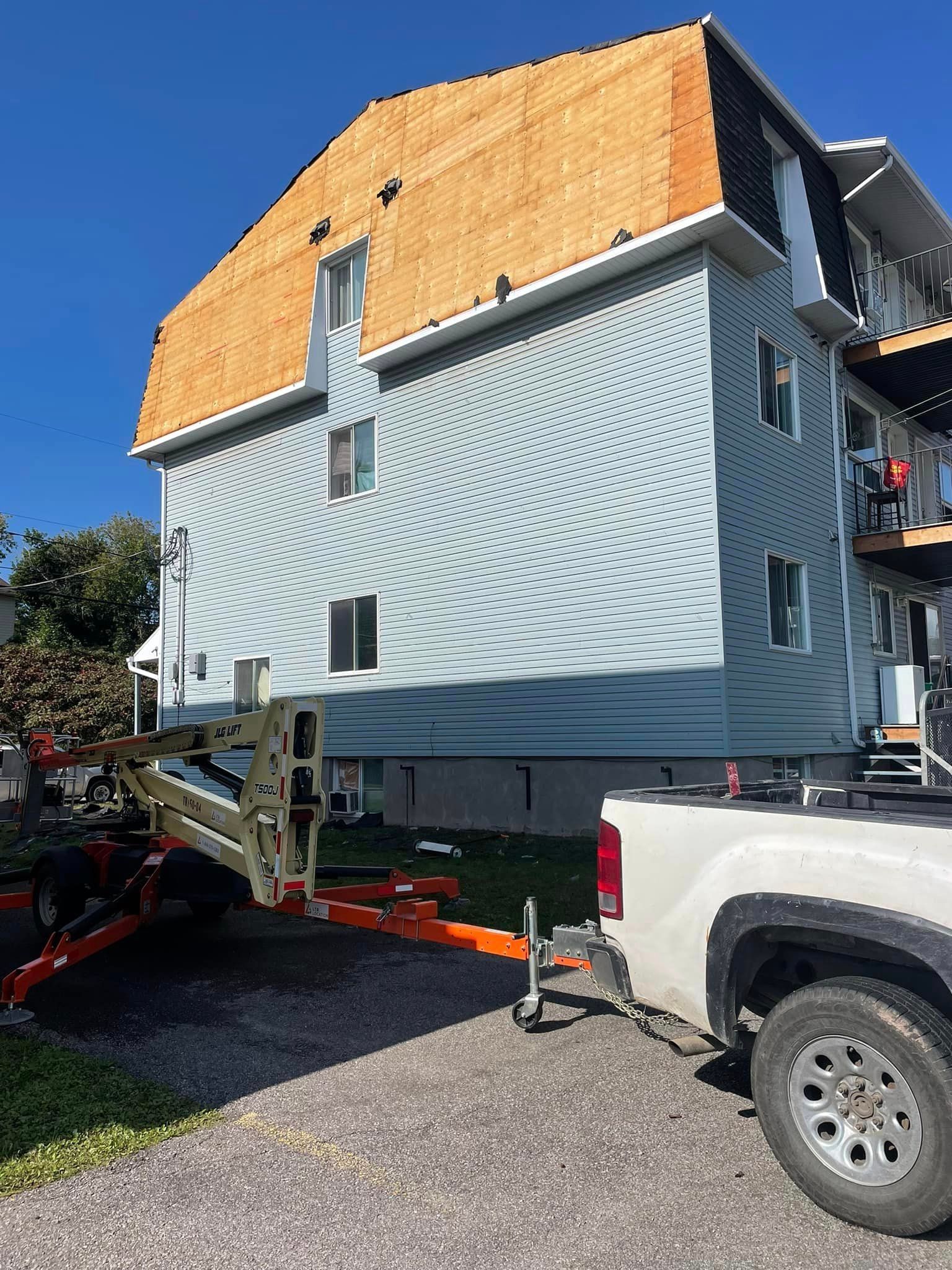 Un camion blanc est garé devant une grande maison.