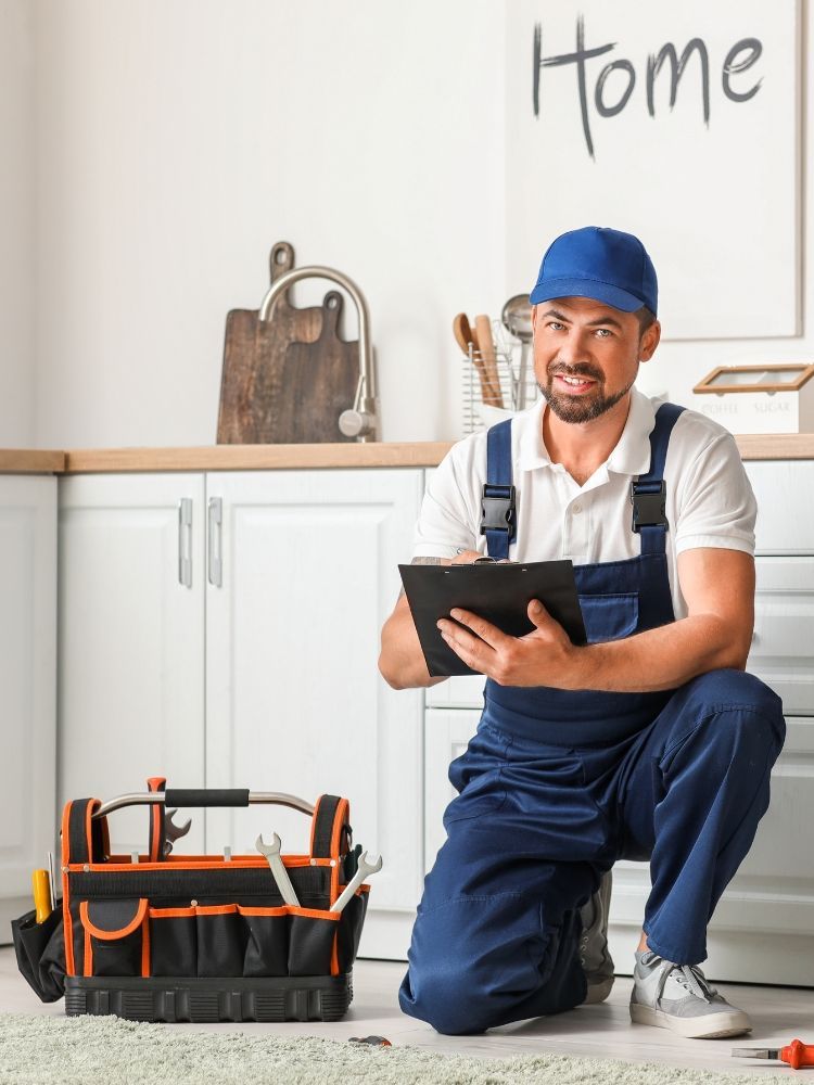 A man in overalls is standing next to an open refrigerator in a kitchen.