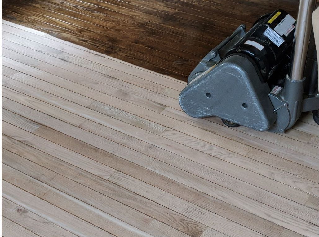 Hardwood floors being sanded as part of the refinishing process