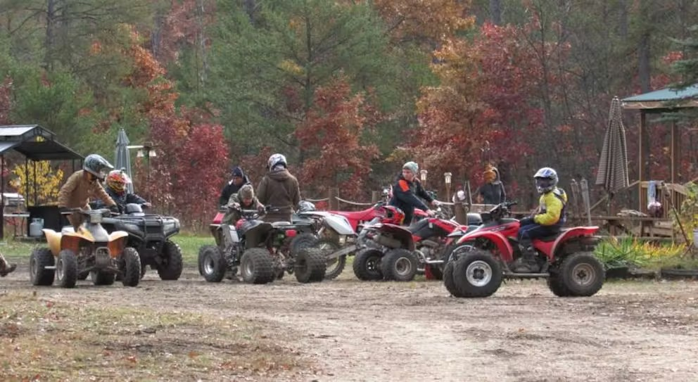 A group of people are riding atvs in a dirt field.